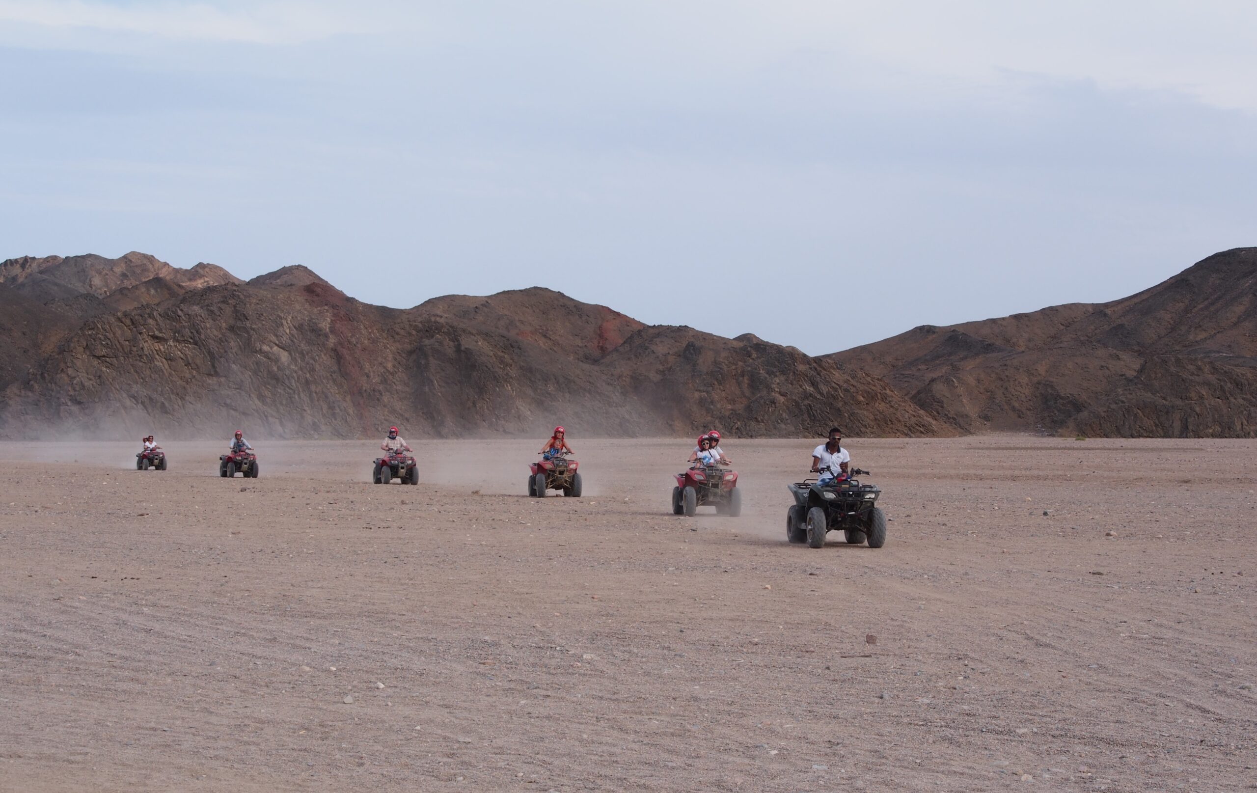 Group quad bike safari in Hurghada desert with scenic dunes and a Bedouin village stop